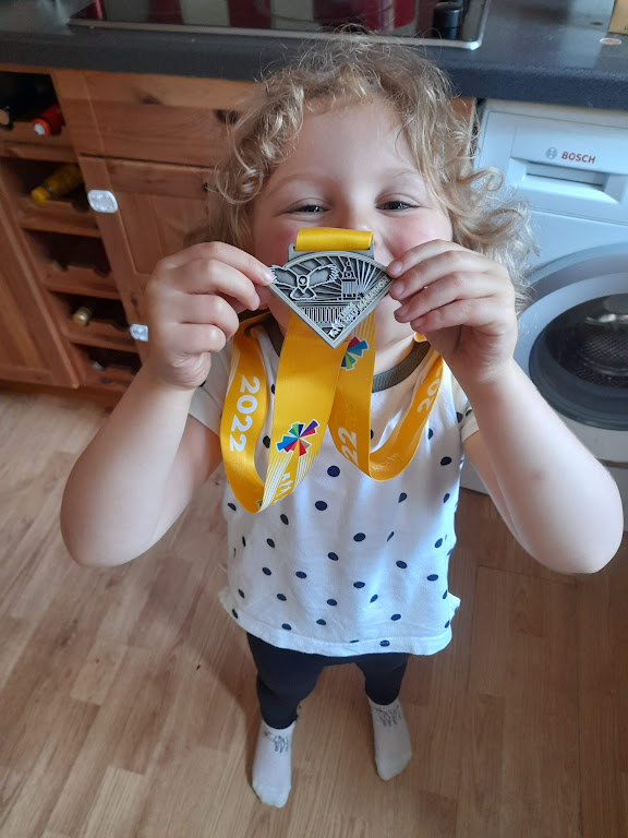 A young girl holds up a running medal