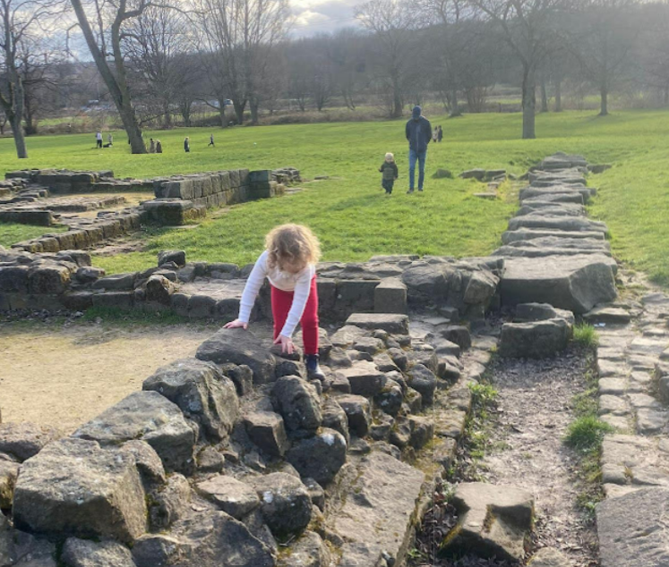 A young girl climbing on the ruined foundations of an old abbey.
