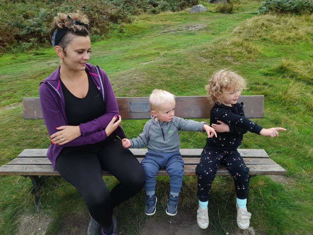 Woman sat on bench with young boy and girl, who are pointing.