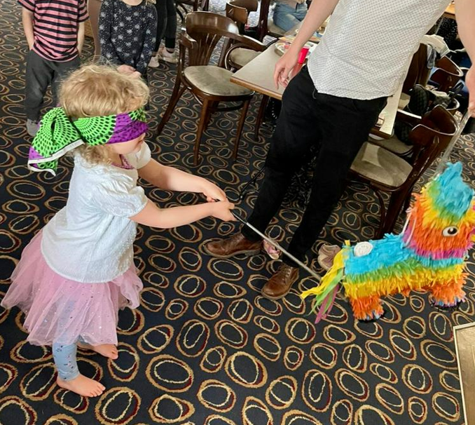 A young girl is blindfolded and hits a pinata with a stick.