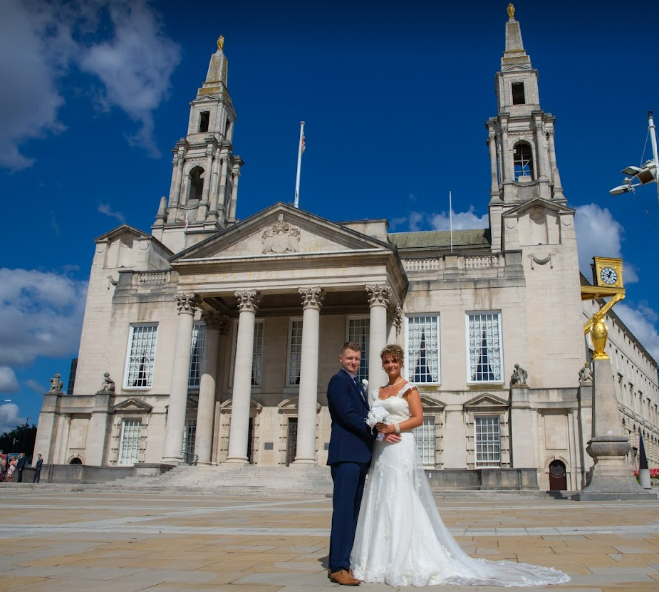 Newly married husband and wife pose outside Leeds Civic Hall