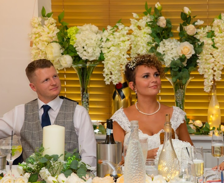 Newly married husband and wife listen to a speech at their wedding reception